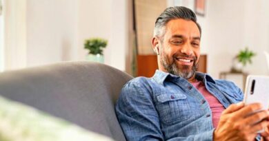 Imagem de homem adulto feliz usando smartphone impactado por marketing digital sentado no sofá.